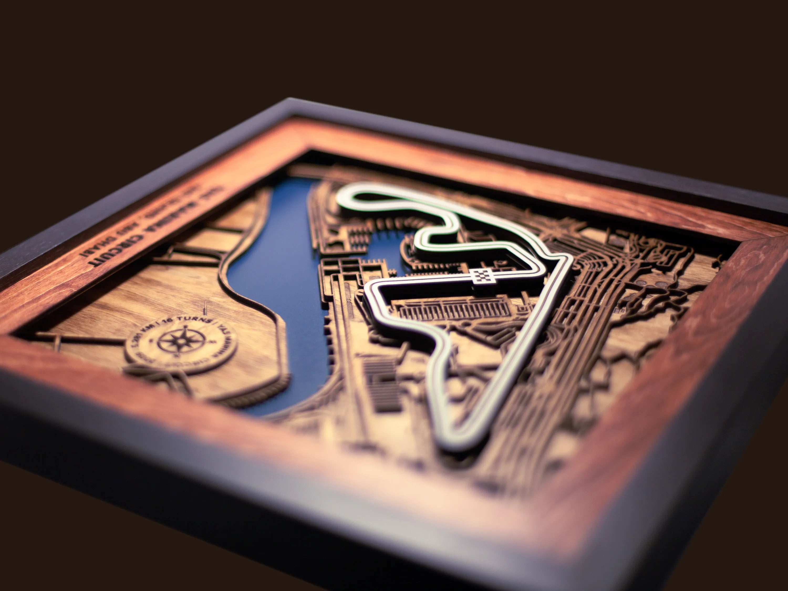 Close-up of the handcrafted layered wood construction and fine details of the Yas Marina Circuit wall art.